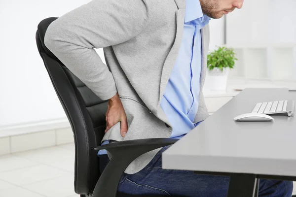 Man with back pain in armchair at office, closeup — Stock Image Man with back pain in armchair at office, closeup Royalty Free Stock Photos