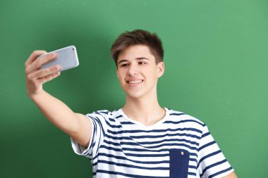 Genç çocuk cep telefonu ile selfie renk arka plan üzerinde yapma
