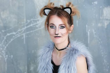 Kedi makyaj ve grunge arka plan kulaklara olan güzel kadın
