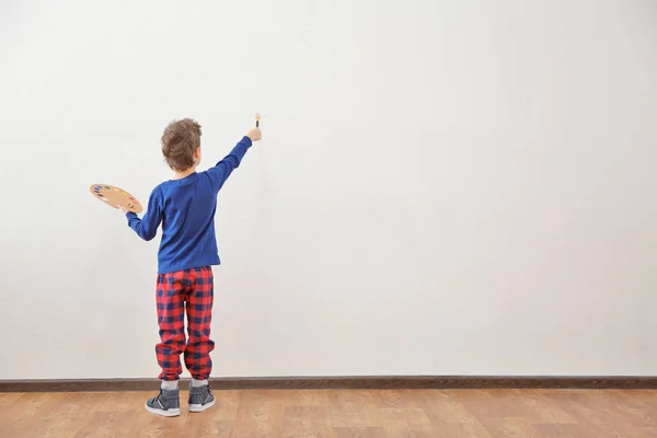 Cute little boy painting on wall in empty room — Stock Photo, Image