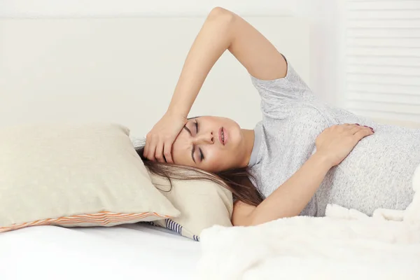 Young pregnant woman suffering from headache while lying in bed at home — Stock Photo, Image