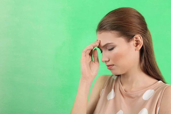 Красивая молодая женщина страдает от головной боли на цветном фоне — стоковое фото