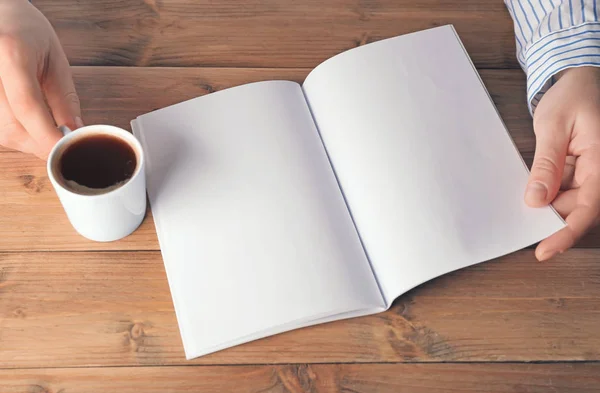 Hands holding blank brochure  and cup of coffee — Stock Photo, Image