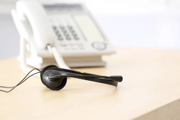 Μαύρο ακουστικό σε τραπέζι με αντιπρόσωπο τεχνικής υποστήριξης στο office — Φωτογραφία Αρχείου