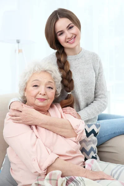Beautiful girl with grandmother on couch at home — Stock Photo, Image
