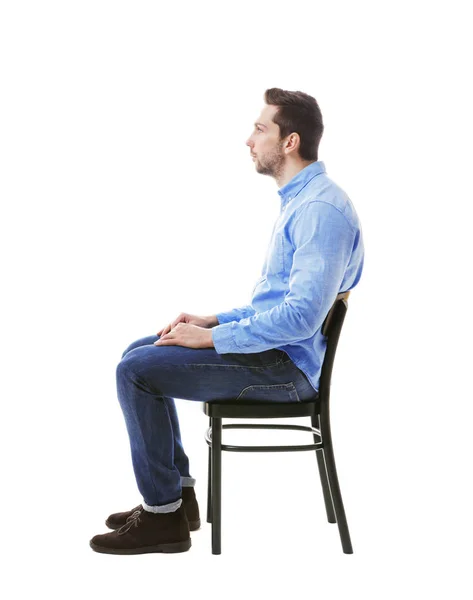Virheellinen asento käsite. Mies istuu tuolilla eristyksissä valkoisella — kuvapankkivalokuva