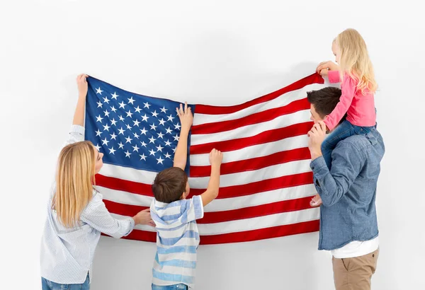 Happy family hanging American flag on wall — Stock Photo, Image