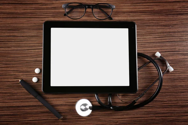 Tablet with stethoscope, pills and glasses — Stock Photo, Image