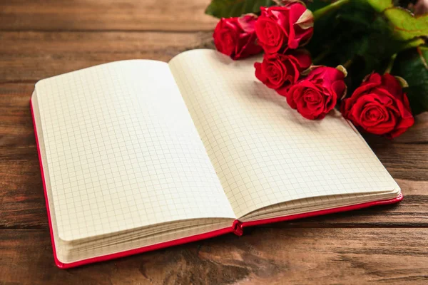 Schöne rote Rosen mit Notizbuch — Stockfoto