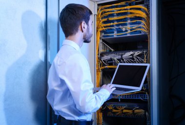 Sunucu odası içinde laptop ile yakışıklı genç mühendis