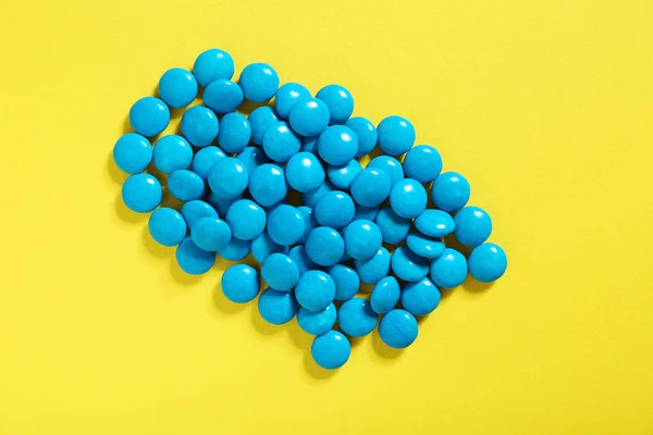 Blauwe snoepjes op geel — Stockfoto