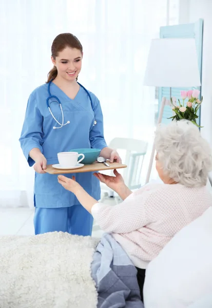 Nurse giving breakfast to elderly woman — Stock Photo, Image