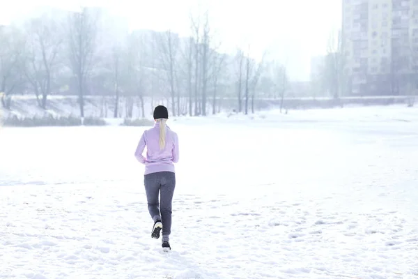 Молодая женщина бежит зимой — стоковое фото