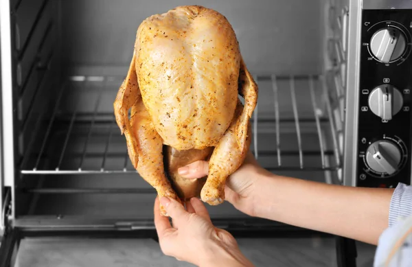 Mujer poniendo pollo en el horno — Foto de Stock