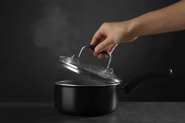 Hand removing cover from saucepan — Stock Photo, Image