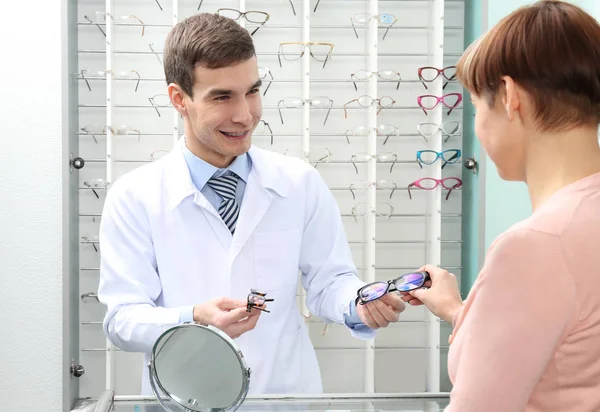 Giovane medico aiuta la donna a scegliere nuovi occhiali in negozio — Foto Stock