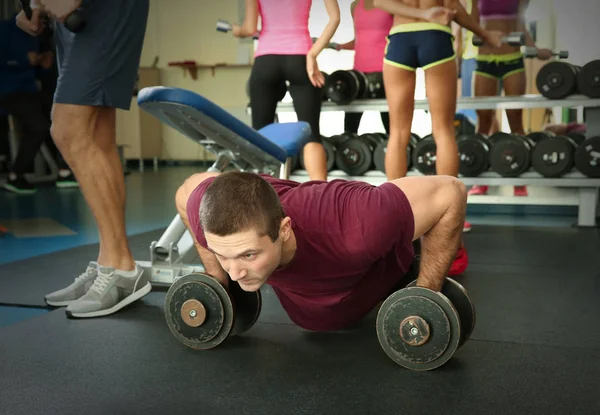 Joven hombre guapo con mancuernas de entrenamiento en el gimnasio —  Fotos de Stock