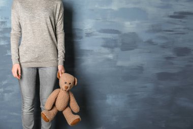 Küçük kız mavi arka plan üzerinde oyuncak ayı ile ayakta