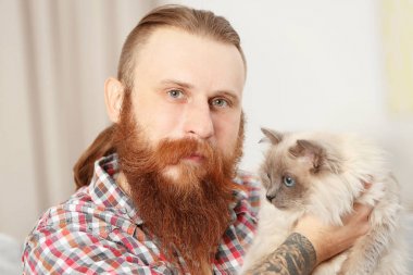 Genç adam ile kabarık kedi evde sakallı