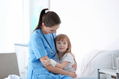Doktor hastane odasında küçük kız kucaklayan