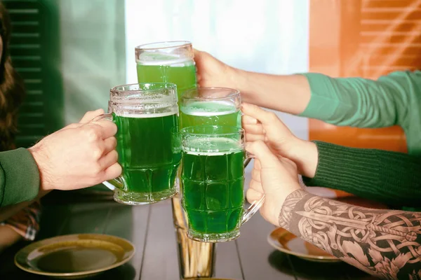 Hands of people with beer celebrating Saint Patrick Day in pub