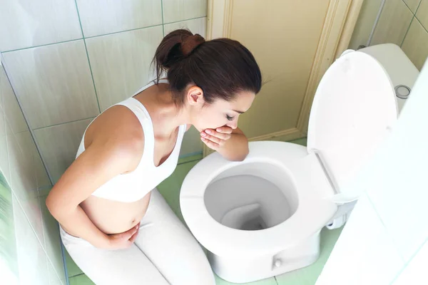 Mujer joven vomitando cerca del inodoro en casa —  Fotos de Stock