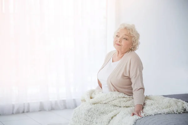 Žena sedí na posteli v místnosti se světlem — Stock fotografie
