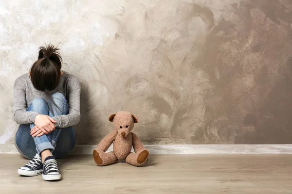 壁の色の背景で熊のぬいぐるみで座っている女の子 — ストック写真