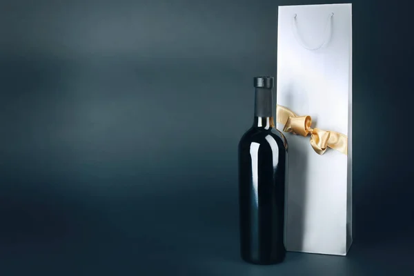 Vin flaska och gåva väska på mörk bakgrund — Stockfoto