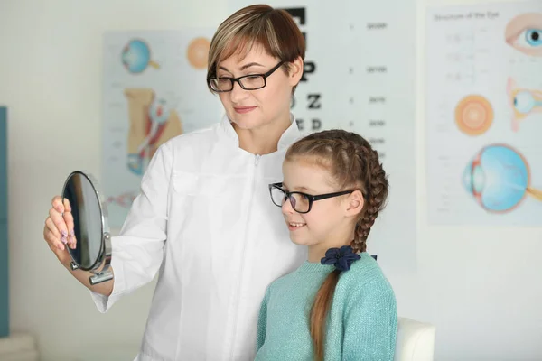 Linda niña probándose unas gafas nuevas en el consultorio del oftalmólogo —  Fotos de Stock