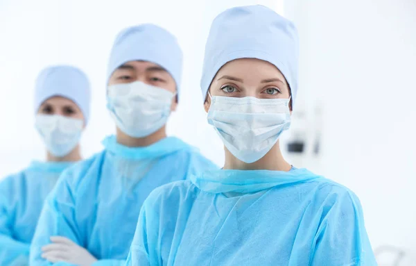 Beautiful young doctor with colleagues in clinic — Stock Photo, Image