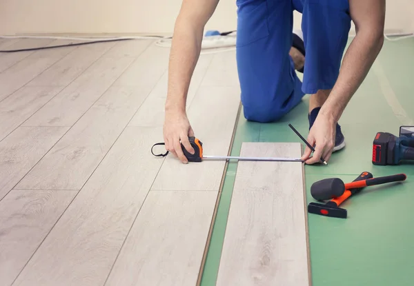 Homem instalando novo piso laminado de madeira — Fotografia de Stock
