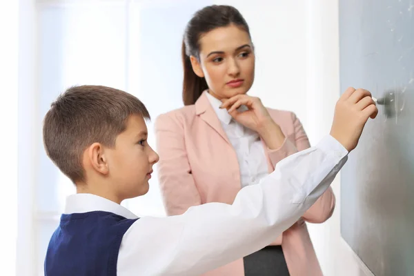 Lärare och skolpojke skriva på tavlan i klassrummet — Stockfoto