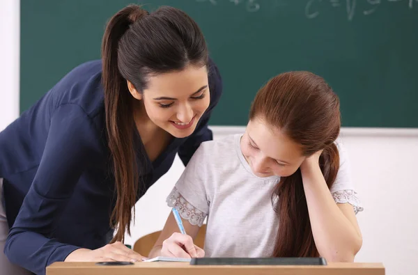 Kvinnlig lärare och skolpojke gör uppgift i klassrummet — Stockfoto