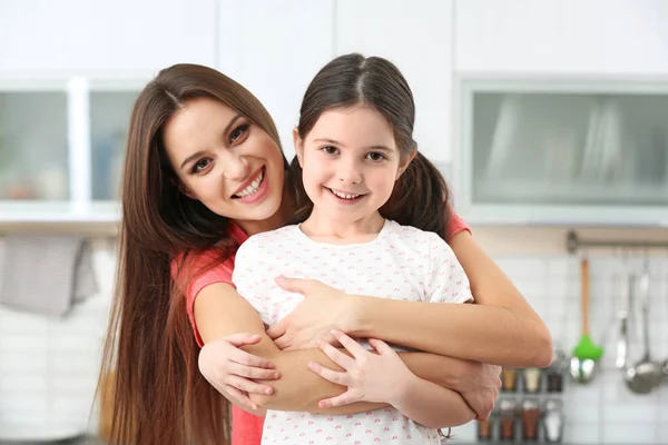年轻的母亲拥抱小女孩在厨房 — 图库照片