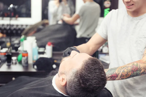 Frisören tar hand om kundens ansikte i barbershop — Stockfoto