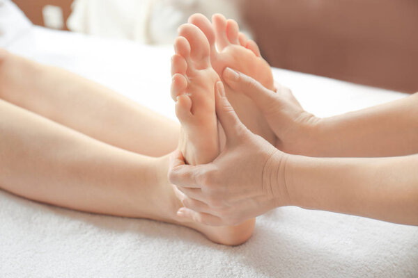 Young woman receiving foot massage in spa salon