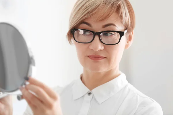 Женщина с зеркалом примеряет очки — стоковое фото