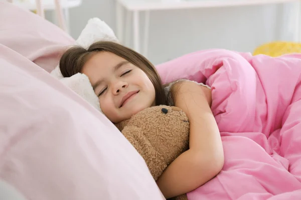 Liten flicka sover i sängen — Stockfoto
