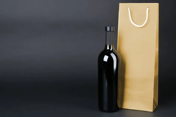Weinflasche und Geschenktüte auf dunklem Hintergrund — Stockfoto