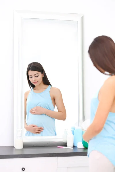 Mulher grávida bonita de pé perto do espelho em casa — Fotografia de Stock