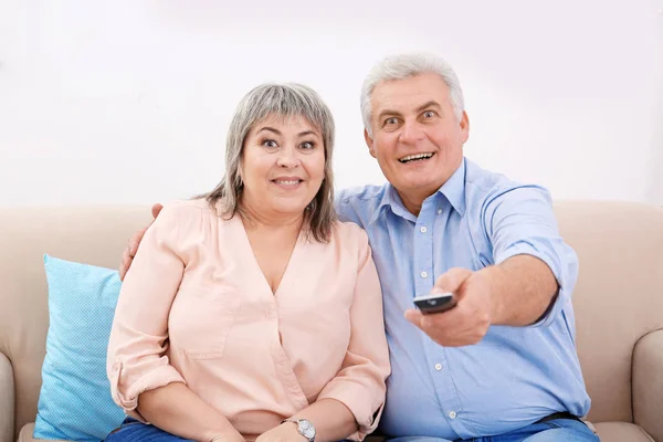 Středního věku pár doma dívat na televizi — Stock fotografie