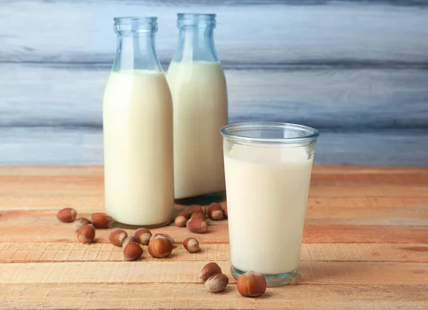 Glas und Flaschen mit Milch und leckeren Haselnüssen — Stockfoto