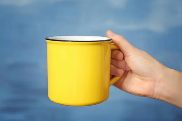 Blank yellow cup in hand — Stock Photo, Image