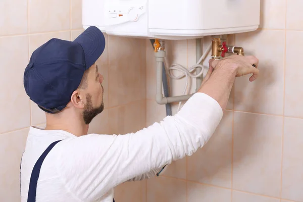 Plumber installing water heater in bathroom — Stock Photo, Image