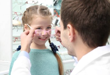 Genç doktor yeni gözlük Dükkanı seçmek için küçük kıza yardım