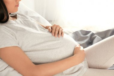 Evde, yatakta closeup dinlenme güzel hamile kadın