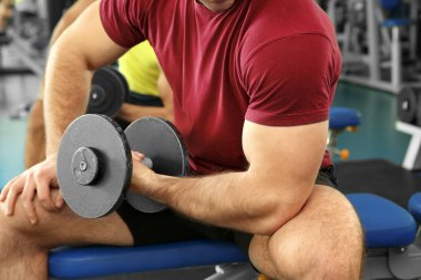 Dumbbell eğitim salonunda genç yakışıklı adamla