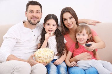 Mutlu bir aile evdeki kanepede televizyon izliyor.