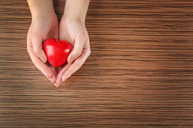 Female hands holding red heart 